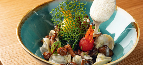 碗中盛有各式食材，包括饺子、蘑菇、蔬菜和装饰性的泡沫，颜色丰富，呈现出独特的美感。